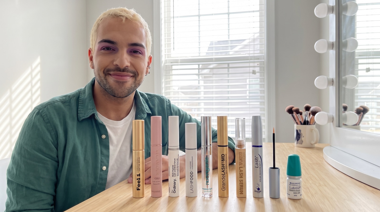 Makeup artist Danny Rose at his kitchen table behind the ten eyelash serums he tested, the gold Feel1 tube front and center