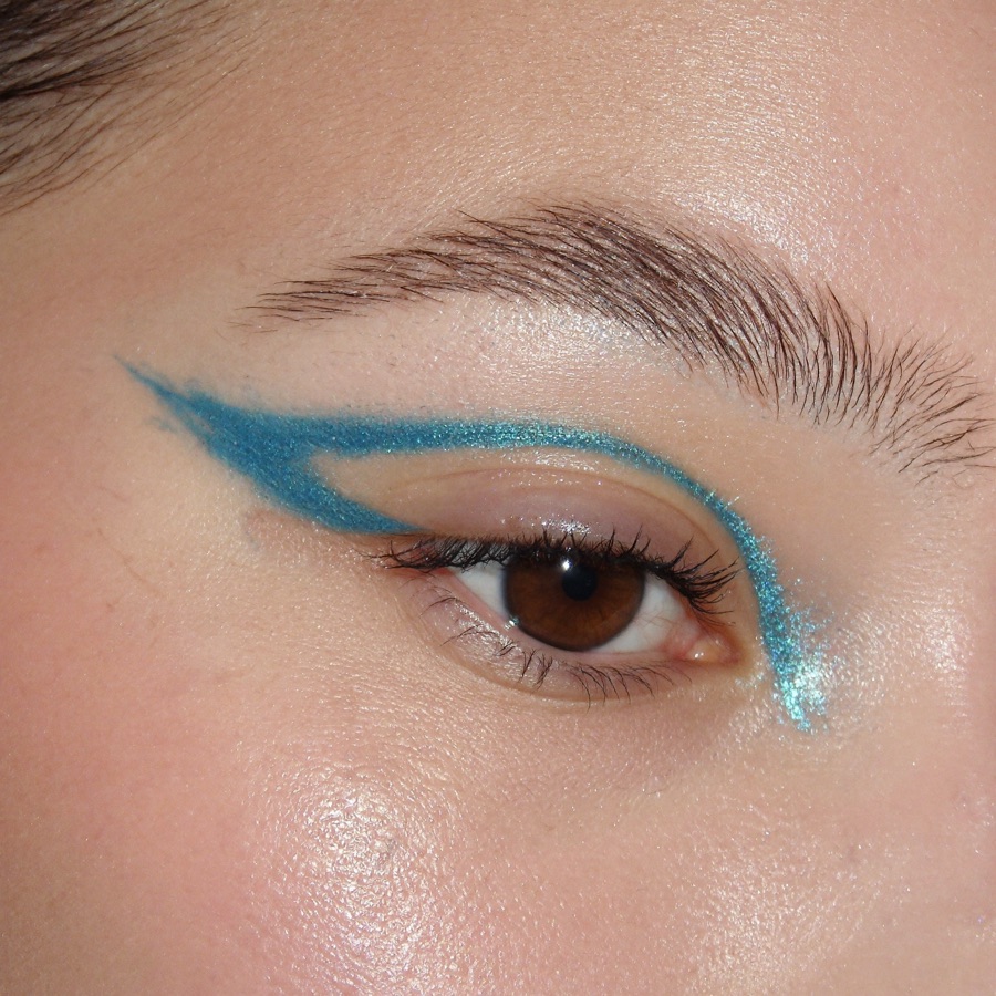 Close-up of a graphic teal eyeliner look with glitter detail