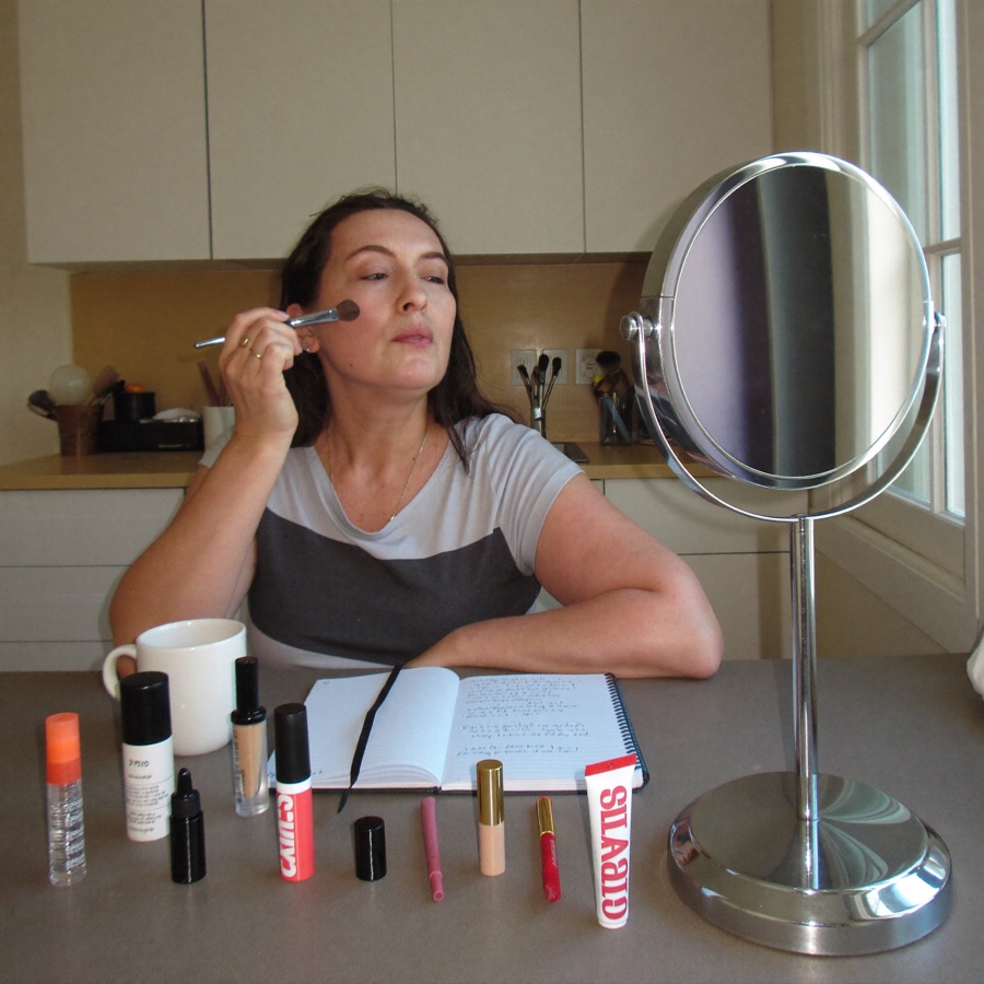 Makeup lesson at a kitchen table with products spread out in daylight