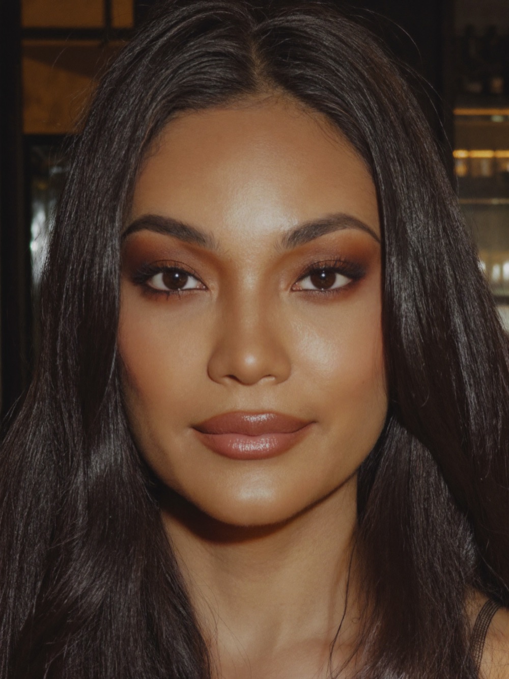 Woman with smoky bronze eye makeup and glossy lip at an evening event