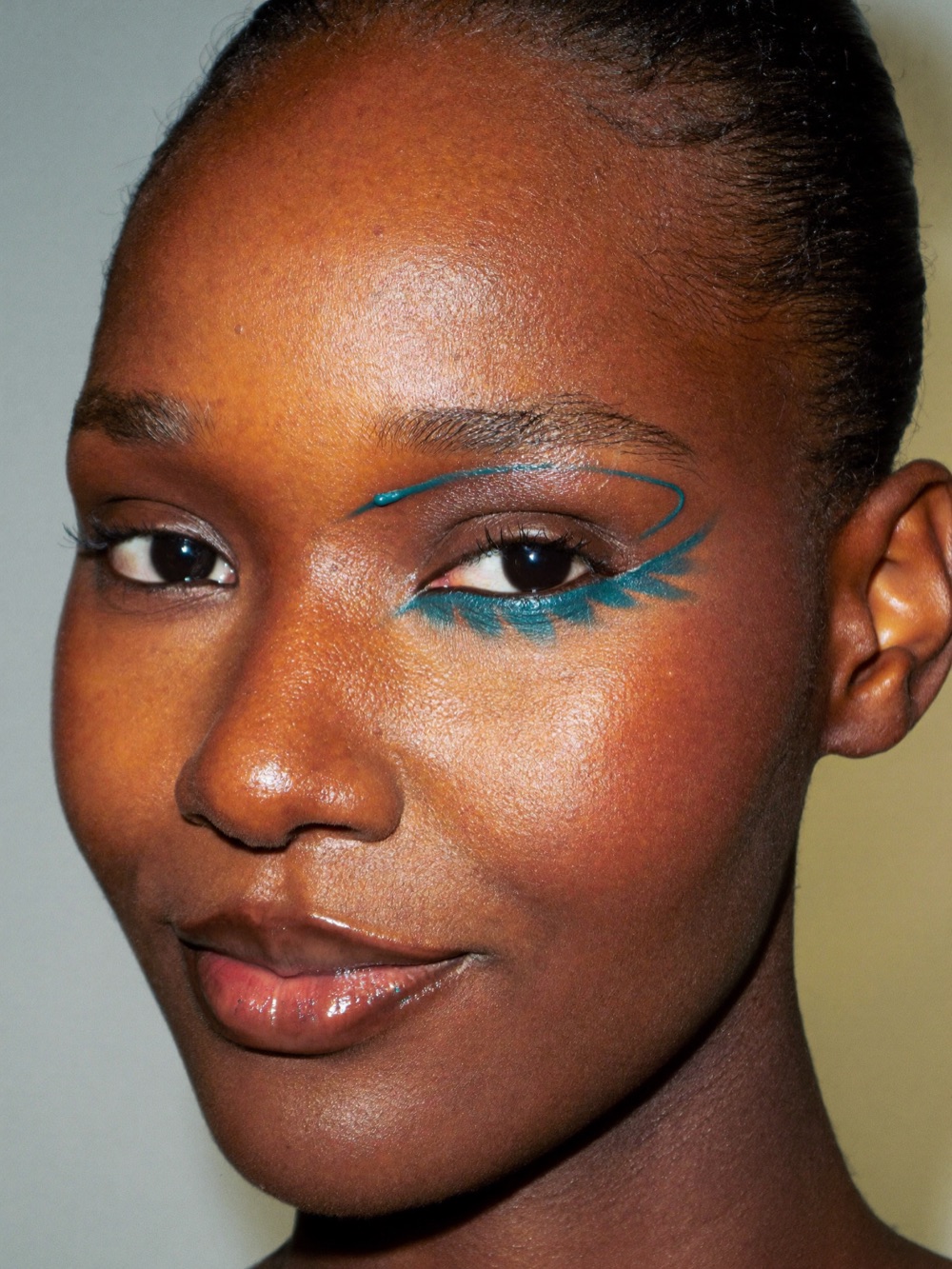 Model with a graphic teal winged liner and clean skin